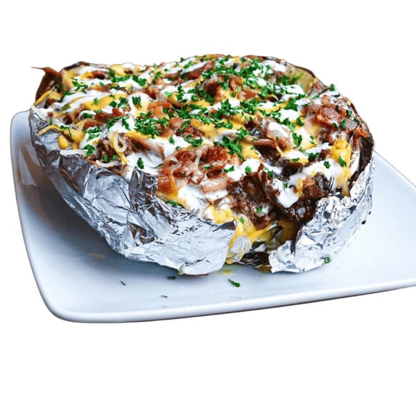 Baked potato in foil, topped with cheese, bacon, sour cream, and parsley on a white plate.