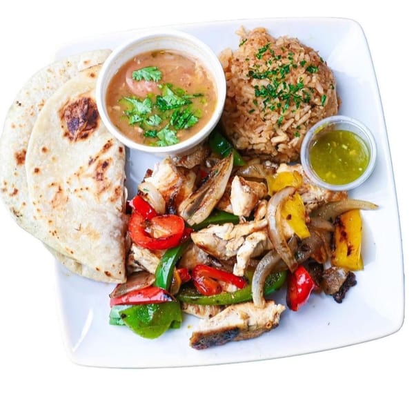 Chicken fajitas with bell peppers and onions, rice, beans, salsa, and tortillas on a white plate.