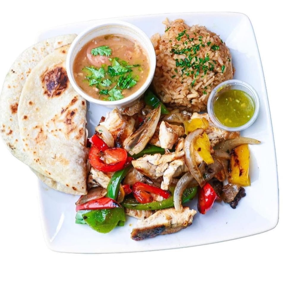 Chicken fajitas with bell peppers and onions, rice, beans, salsa, and tortillas on a white plate.